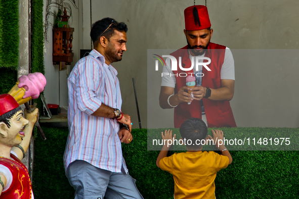 A Turkish ice cream vendor is performing tricks as he entertains a young boy along the Mall Road in Mussoorie, Uttarakhand, India, on April...