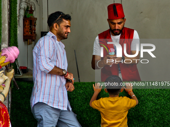 A Turkish ice cream vendor is performing tricks as he entertains a young boy along the Mall Road in Mussoorie, Uttarakhand, India, on April...