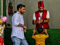 A Turkish ice cream vendor is performing tricks as he entertains a young boy along the Mall Road in Mussoorie, Uttarakhand, India, on April...