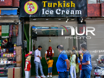 A Turkish ice cream vendor is performing tricks as he entertains a young boy along the Mall Road in Mussoorie, Uttarakhand, India, on April...