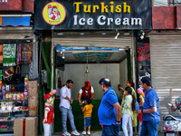 A Turkish ice cream vendor is performing tricks as he entertains a young boy along the Mall Road in Mussoorie, Uttarakhand, India, on April...