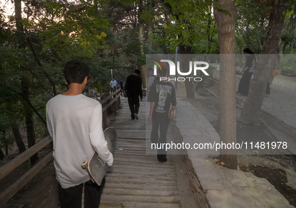 Young Iranian skaters are walking together at a park in central Tehran, Iran, on August 15, 2024. 