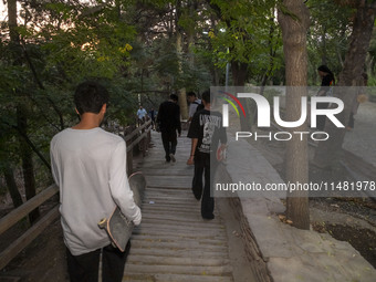 Young Iranian skaters are walking together at a park in central Tehran, Iran, on August 15, 2024. (