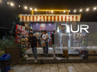 Afghan youths are standing in front of a snack stand at a park in central Tehran, Iran, on August 15, 2024. (