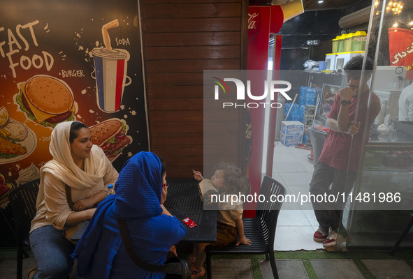 An Iranian family is sitting at an outdoor restaurant at a park in central Tehran, Iran, on August 15, 2024. 