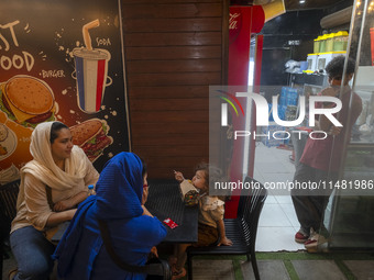 An Iranian family is sitting at an outdoor restaurant at a park in central Tehran, Iran, on August 15, 2024. (