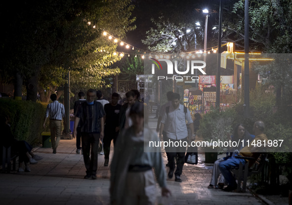 Iranian people are walking along a sidewalk at a park in central Tehran, Iran, on August 15, 2024. 