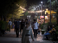 Iranian people are walking along a sidewalk at a park in central Tehran, Iran, on August 15, 2024. (