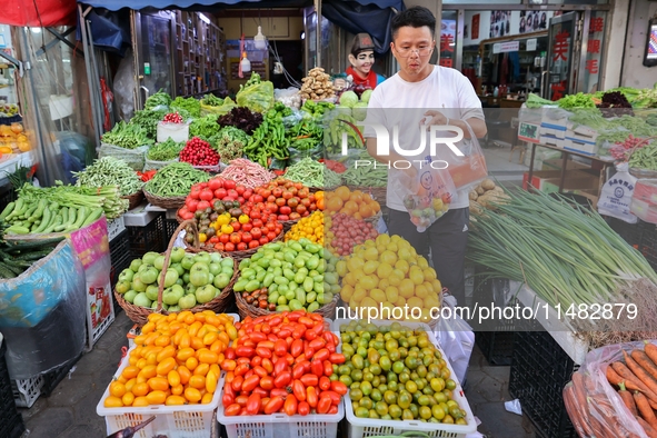 Customers are shopping at a fruit market next to Manzhouli Zhongsu Pedestrian Street in Hohhot, Inner Mongolia, China, on August 15, 2024. 