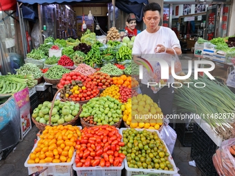 Customers are shopping at a fruit market next to Manzhouli Zhongsu Pedestrian Street in Hohhot, Inner Mongolia, China, on August 15, 2024. (