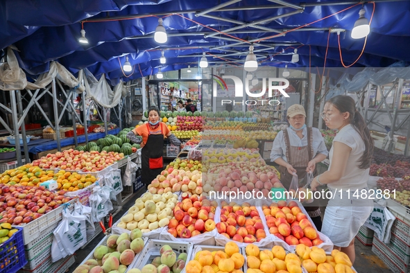 Customers are shopping at a fruit market next to Manzhouli Zhongsu Pedestrian Street in Hohhot, Inner Mongolia, China, on August 15, 2024. 