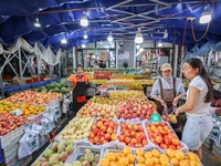 Customers are shopping at a fruit market next to Manzhouli Zhongsu Pedestrian Street in Hohhot, Inner Mongolia, China, on August 15, 2024. (