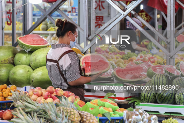 Customers are shopping at a fruit market next to Manzhouli Zhongsu Pedestrian Street in Hohhot, Inner Mongolia, China, on August 15, 2024. 