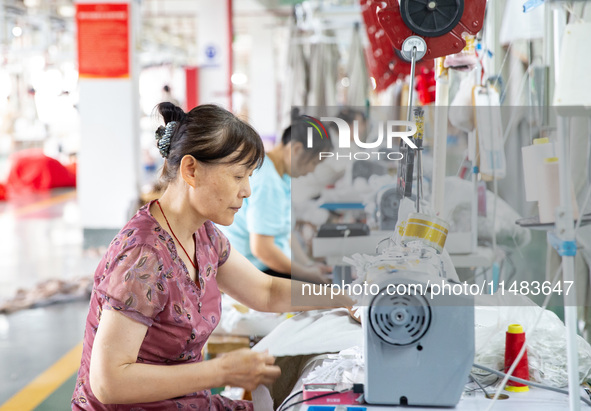 Workers are working on a production line at a workshop of a textile company in Nantong, Jiangsu province, China, on August 15, 2024. 