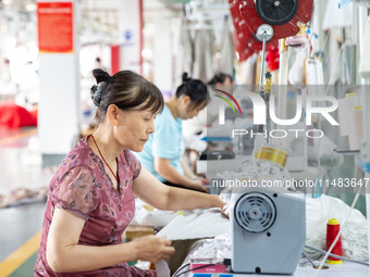 Workers are working on a production line at a workshop of a textile company in Nantong, Jiangsu province, China, on August 15, 2024. (