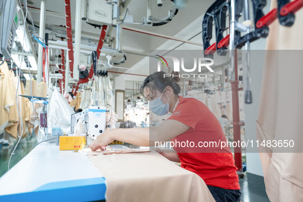 A worker is working on a production line at a workshop of a textile company in Nantong, China, on August 15, 2024. 