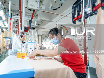 A worker is working on a production line at a workshop of a textile company in Nantong, China, on August 15, 2024. (