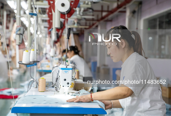 A worker is working on a production line at a workshop of a textile company in Nantong, China, on August 15, 2024. 