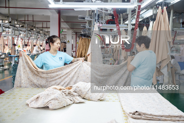 Workers are working on a production line at a workshop of a textile company in Nantong, Jiangsu province, China, on August 15, 2024. 