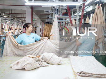 Workers are working on a production line at a workshop of a textile company in Nantong, Jiangsu province, China, on August 15, 2024. (