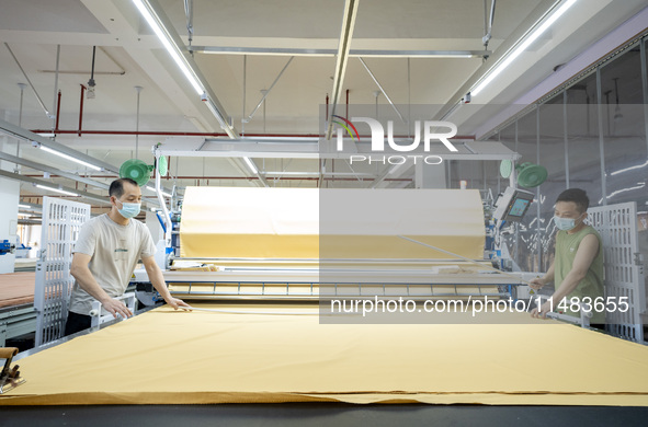 Workers are working on a production line at a workshop of a textile company in Nantong, Jiangsu province, China, on August 15, 2024. 