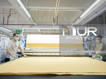 Workers are working on a production line at a workshop of a textile company in Nantong, Jiangsu province, China, on August 15, 2024. (