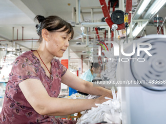 A worker is working on a production line at a workshop of a textile company in Nantong, China, on August 15, 2024. (