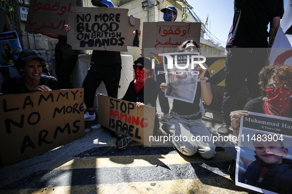 Chained Israeli protesters are holding placards in a protest to call for an end to the war in Gaza, during Britain's Foreign Secretary David...