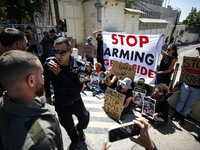 Chained Israeli protesters are holding placards in a protest to call for an end to the war in Gaza, during Britain's Foreign Secretary David...