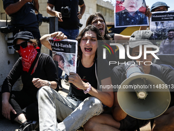 Chained Israeli protesters are holding placards in a protest to call for an end to the war in Gaza, during Britain's Foreign Secretary David...