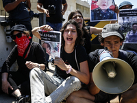 Chained Israeli protesters are holding placards in a protest to call for an end to the war in Gaza, during Britain's Foreign Secretary David...