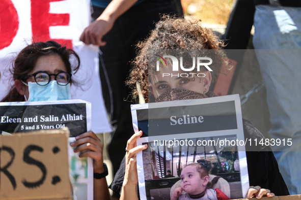 Chained Israeli protesters are holding placards in a protest to call for an end to the war in Gaza, during Britain's Foreign Secretary David...