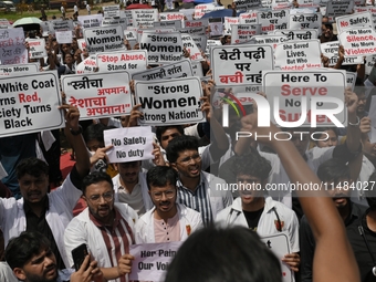 Medical professionals are shouting slogans and holding placards to protest against the rape and murder of a trainee medic at a government-ru...