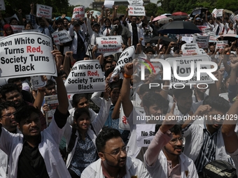 Medical professionals are shouting slogans and holding placards to protest against the rape and murder of a trainee medic at a government-ru...