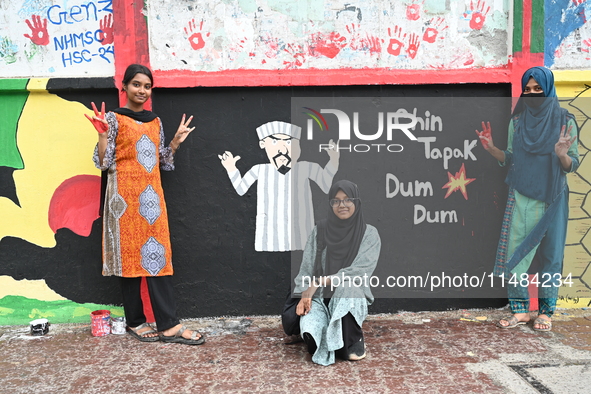 Students are showing their painted hands while painting graffiti on a wall alongside a road to express their message after the fall of Bangl...