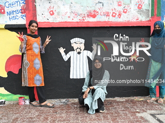 Students are showing their painted hands while painting graffiti on a wall alongside a road to express their message after the fall of Bangl...