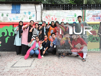 Students are showing their painted hands while painting graffiti on a wall alongside a road to express their message after the fall of Bangl...