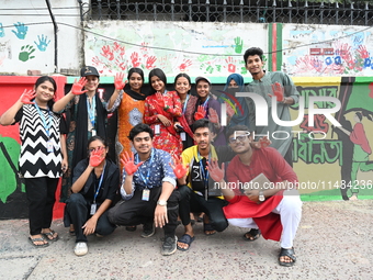 Students are showing their painted hands while painting graffiti on a wall alongside a road to express their message after the fall of Bangl...