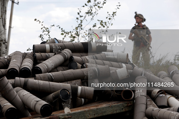 An armed soldier is standing behind a pile of used shells at the positions of the Motorised Rifle Battalion of the 93rd Kholodnyi Yar Separa...