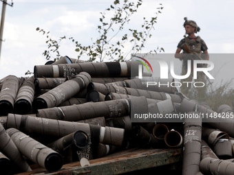 An armed soldier is standing behind a pile of used shells at the positions of the Motorised Rifle Battalion of the 93rd Kholodnyi Yar Separa...