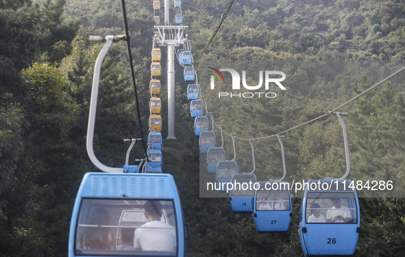 Tourists are riding ropeways at Lianhua Mountain in Dalian, China, on August 15, 2024. 