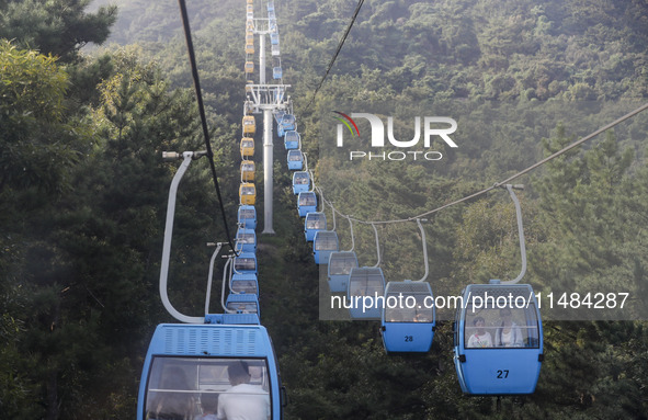 Tourists are riding ropeways at Lianhua Mountain in Dalian, China, on August 15, 2024. 