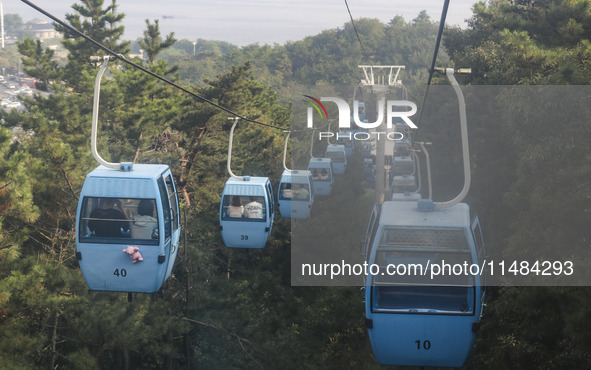 Tourists are riding ropeways at Lianhua Mountain in Dalian, China, on August 15, 2024. 