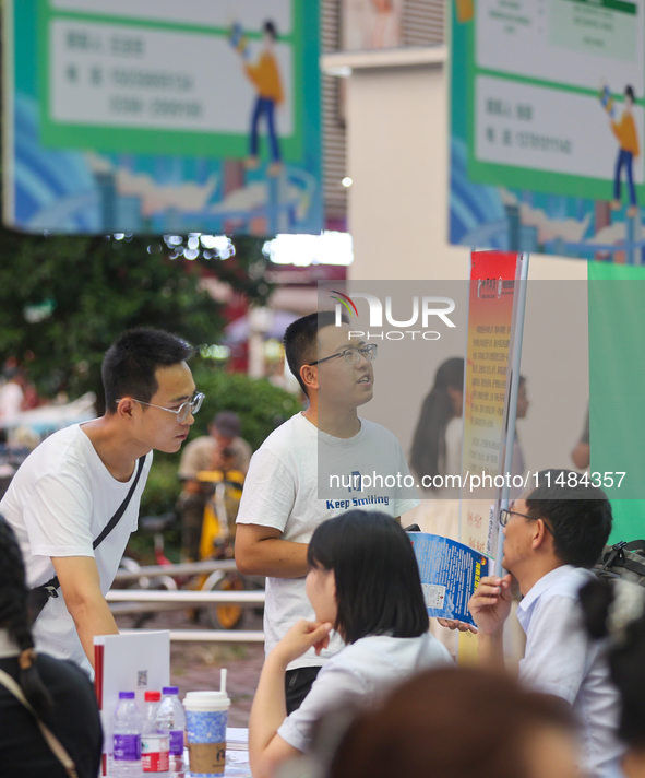 Job seekers are looking for information at a night market recruitment fair in Sanmenxia, China, on August 16, 2024. 