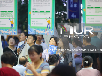 Job seekers are looking for information at a night market recruitment fair in Sanmenxia, China, on August 16, 2024. (