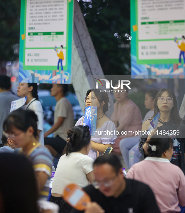 Job seekers are looking for information at a night market recruitment fair in Sanmenxia, China, on August 16, 2024. 