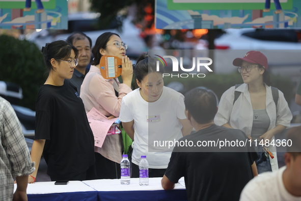 Job seekers are looking for information at a night market recruitment fair in Sanmenxia, China, on August 16, 2024. 