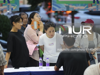 Job seekers are looking for information at a night market recruitment fair in Sanmenxia, China, on August 16, 2024. (