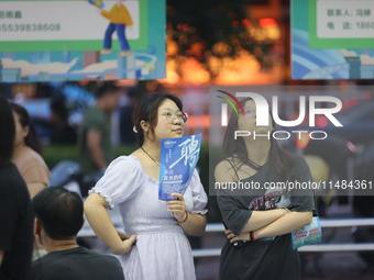 Job seekers are looking for information at a night market recruitment fair in Sanmenxia, China, on August 16, 2024. (