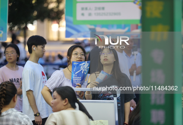 Job seekers are looking for information at a night market recruitment fair in Sanmenxia, China, on August 16, 2024. 